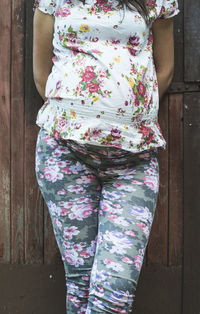 Midsection of pregnant woman standing against wooden door