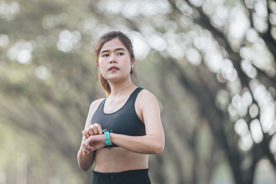 Portrait of young woman gesturing against trees