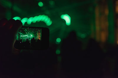 Man photographing entertainment event with smartphone at night