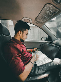 Side view of young man using mobile phone