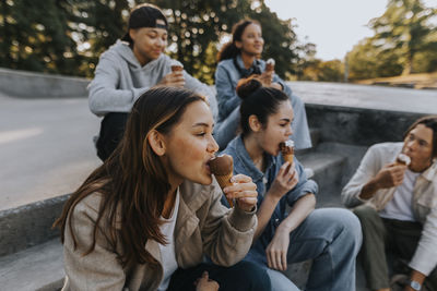 Teenagers sitting in skate park and eating ice cream