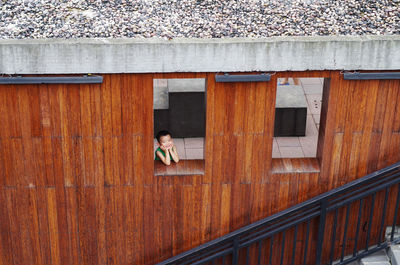 Woman standing on wooden wall