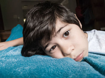 Close-up portrait of boy lying on bed at home