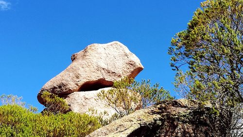 Low angle view of rocks against clear blue sky