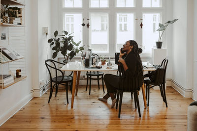 Young female professional talking on mobile phone sitting in home office