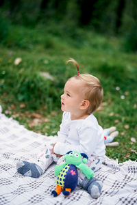 Cute boy with toy sitting outdoors