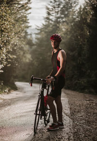 Young man standing by bicycle on road