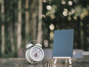 Close-up of clock and blank blackboard on table