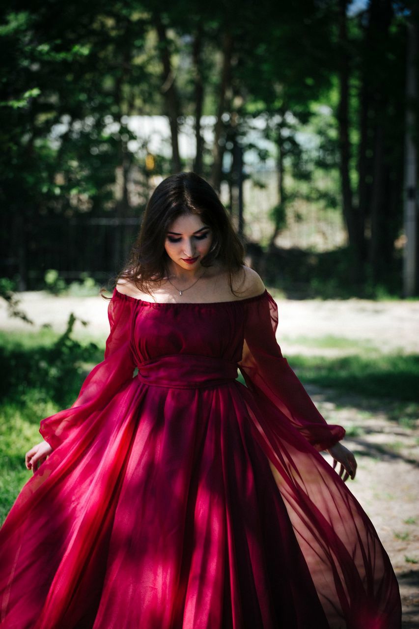 red, fashion, women, clothing, dress, one person, gown, adult, portrait, young adult, tree, hairstyle, long hair, elegance, pink, nature, forest, plant, female, photo shoot, looking at camera, brown hair, outdoors, land, front view, glamour, standing, maroon, formal wear, teenager, full length, focus on foreground, celebration, evening gown, beauty in nature, child