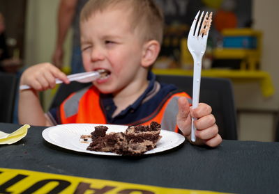 Little toddler sitting at the table and eating cake