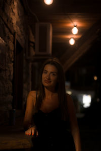 Portrait of young woman standing against wall