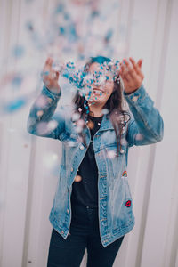 Woman throwing confetti while against wall