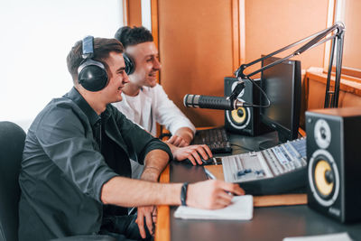 Two guys is indoors in the radio studio is busy by broadcast.