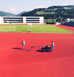 People with umbrella on field against mountain range