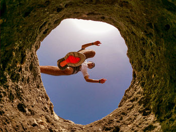 Low angle view of man jumping on rock formation