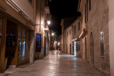 Illuminated alley amidst residential buildings in old town at night