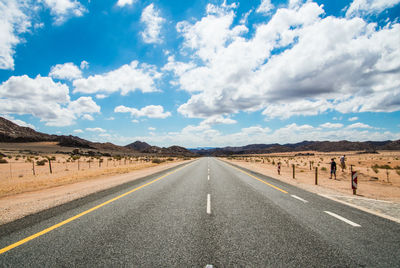 Road by desert landscape against sky