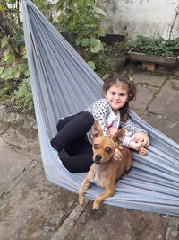 Portrait of cute girl with dog sitting outdoors