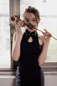 Young woman blowing bubbles while standing against wall