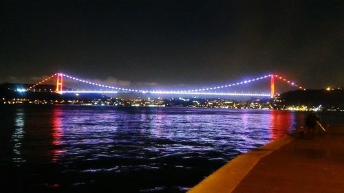 View of suspension bridge over river at night