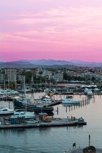 Sailboats moored at harbor against sky during sunset