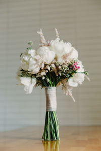 Close-up of white flower vase on table against wall