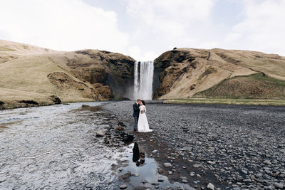 Woman standing on rock against sky