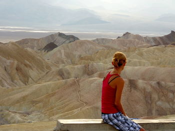 Rear view of man looking at mountains against sky