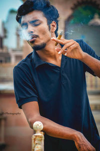 Young man smoking cigarette outdoors