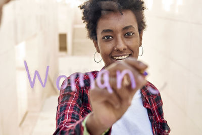 Portrait of a smiling young woman holding camera