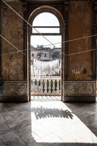 Clothesline hanging in balcony seen through archway of old home