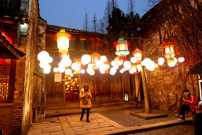 Man and woman walking on illuminated street at night