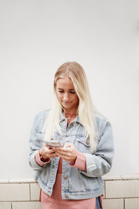 Young woman smiling while standing against wall