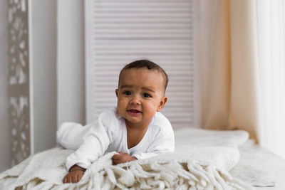 Portrait of cute baby on bed at home