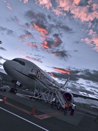 People at airport runway against sky during sunset