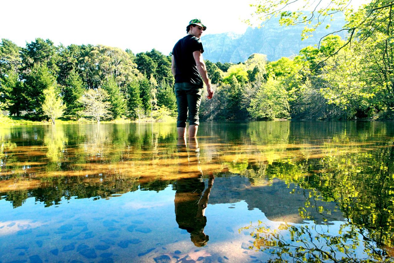 water, reflection, lake, tree, tranquility, leisure activity, waterfront, full length, lifestyles, tranquil scene, nature, standing, casual clothing, beauty in nature, scenics, day, young adult, forest