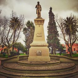 Statue by historic building against sky