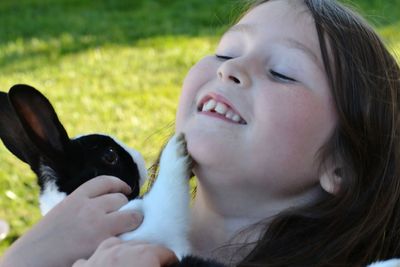 Close-up of girl holding rabbit on field