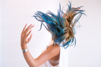 Side view of woman tossing hair against white background