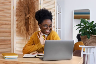 Young woman using phone while sitting on table