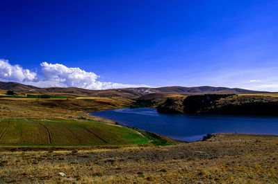 Scenic view of lake and mountains against blue sky