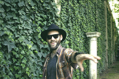 Bearded man standing against ivy