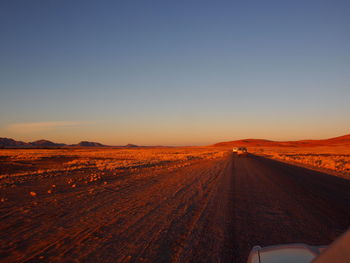 Scenic view of road against clear sky during sunset