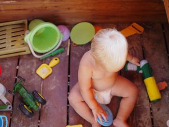 High angle view of boy playing with toys on floorboard