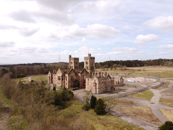 Old building on landscape against cloudy sky