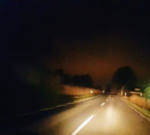 Road amidst trees against sky at night