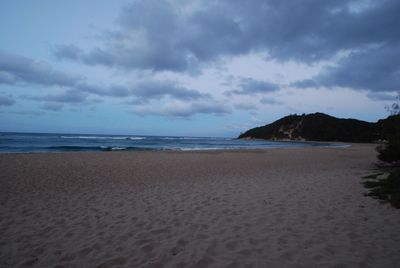 Scenic view of beach against cloudy sky