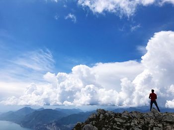 Rear view of man standing on rock against blue sky