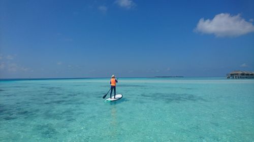 Woman paddleboarding in sea against sky