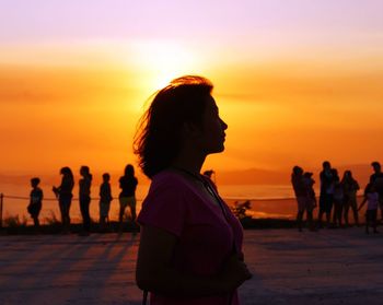 Silhouette people on beach against sky during sunset